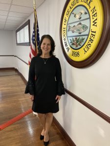 Council Member Condos standing in front of the American Flag and the Borough Seal